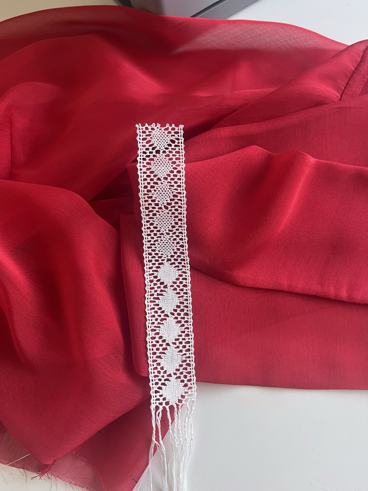 Encaje de bolillos blanco sobre gasa de seda roja