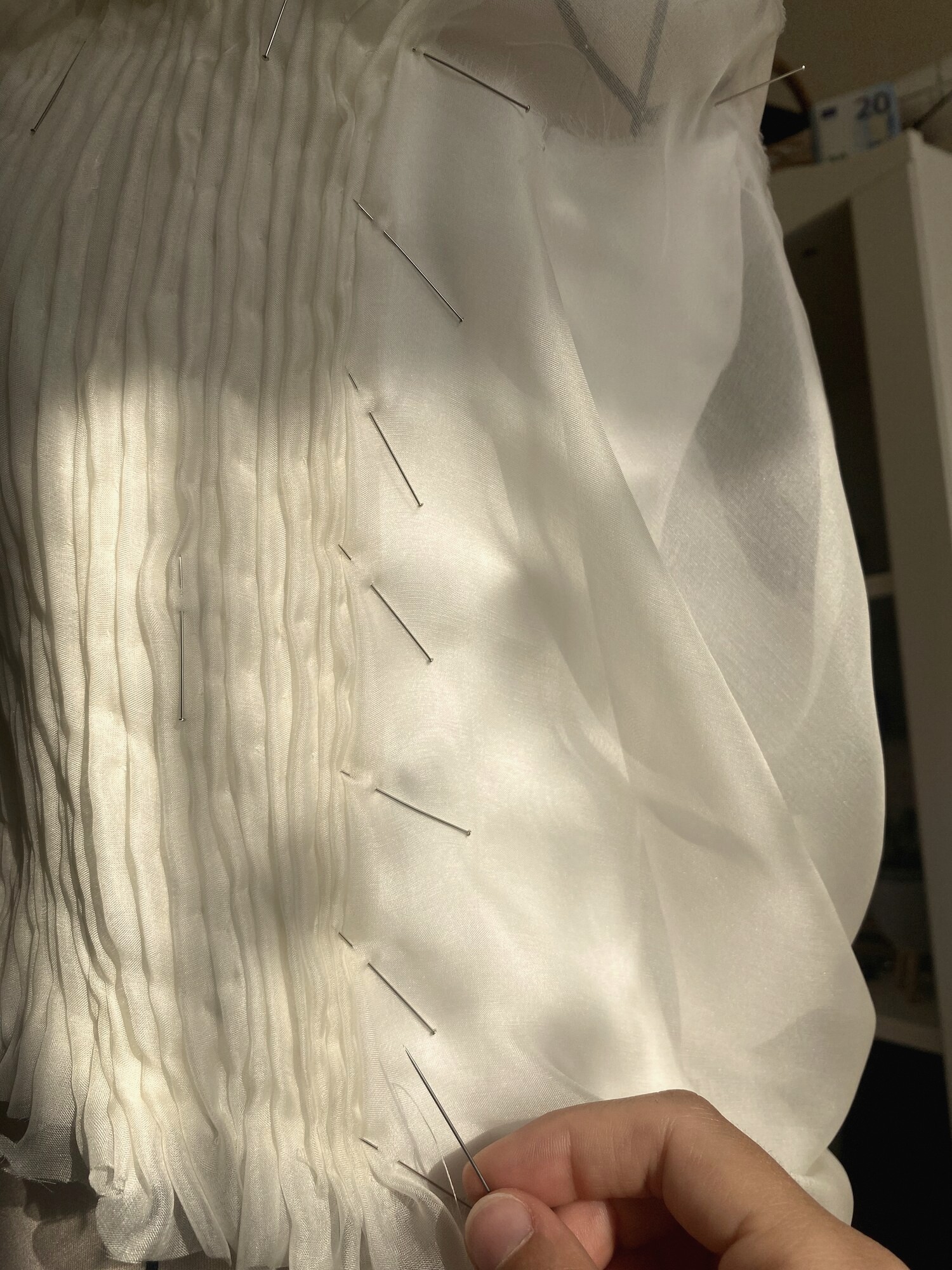 Mano cosiendo a mano sobre organza plisada