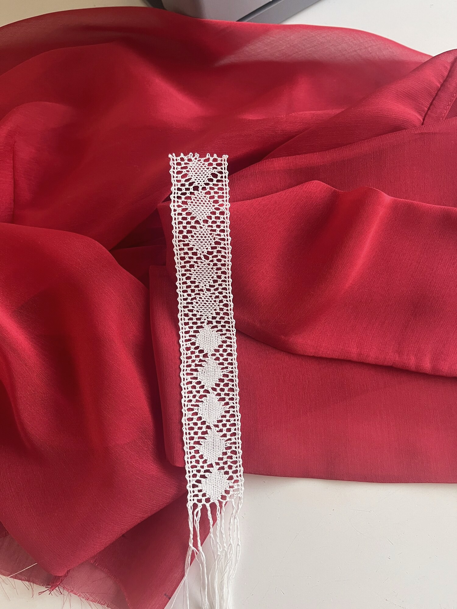 Encaje de bolillos terminado sobre organza roja