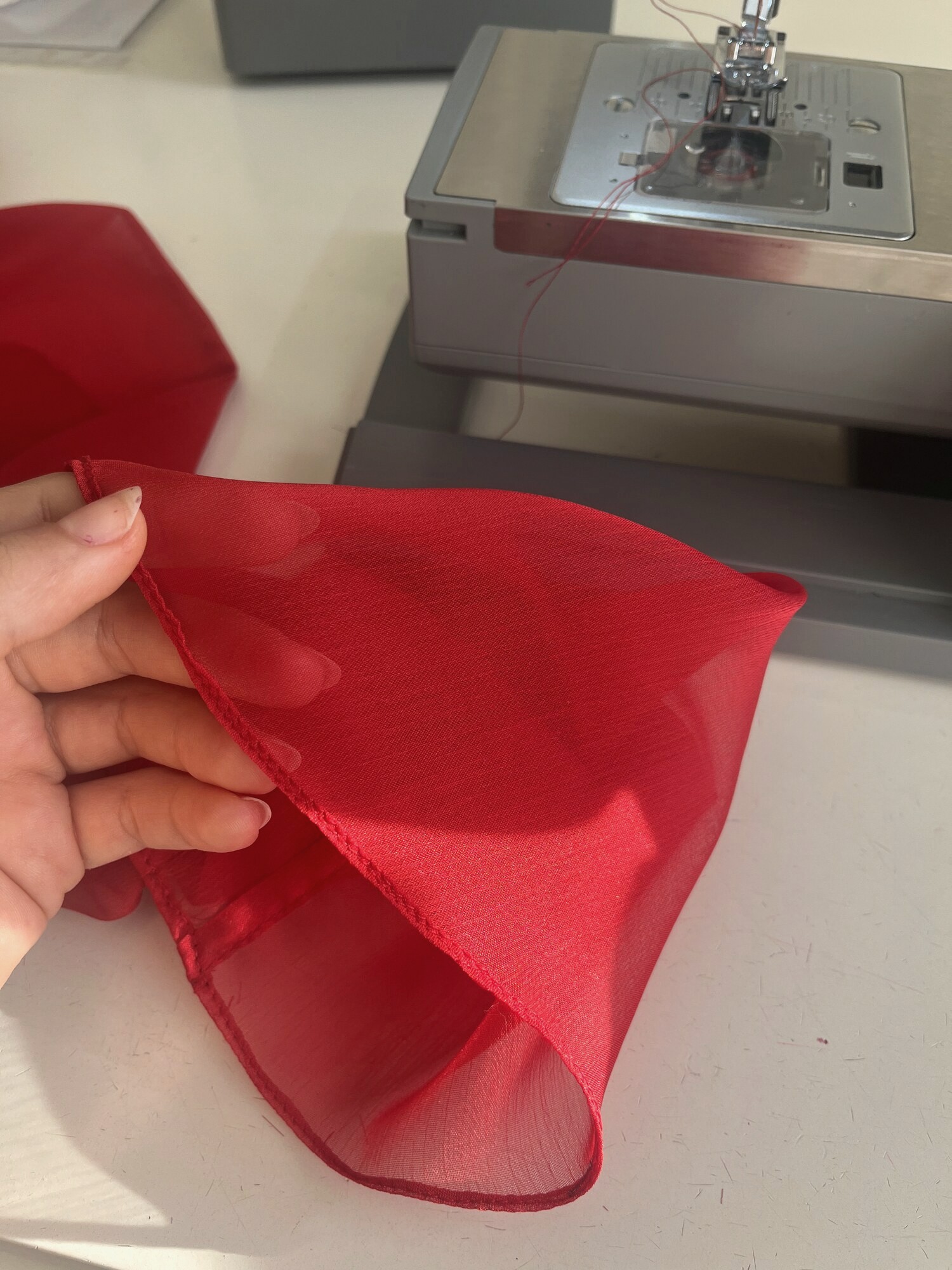 Tela roja traslúcida junto a la máquina de coser
