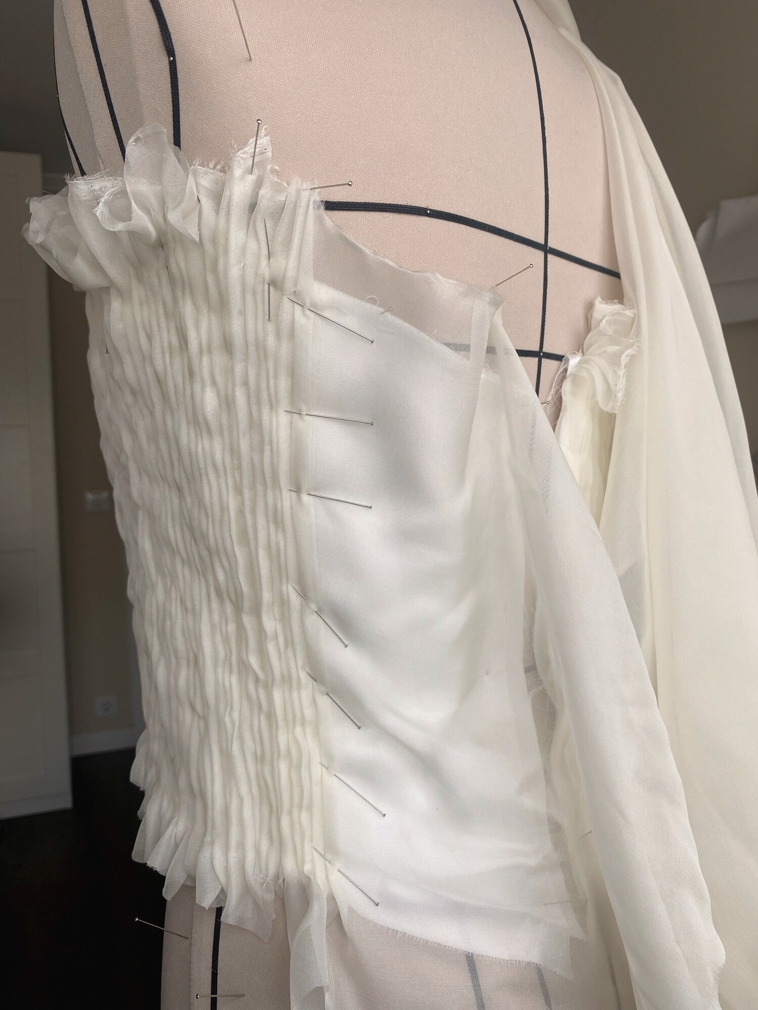 Corpiño plisado blanco en construcción sobre maniquí, con alfileres